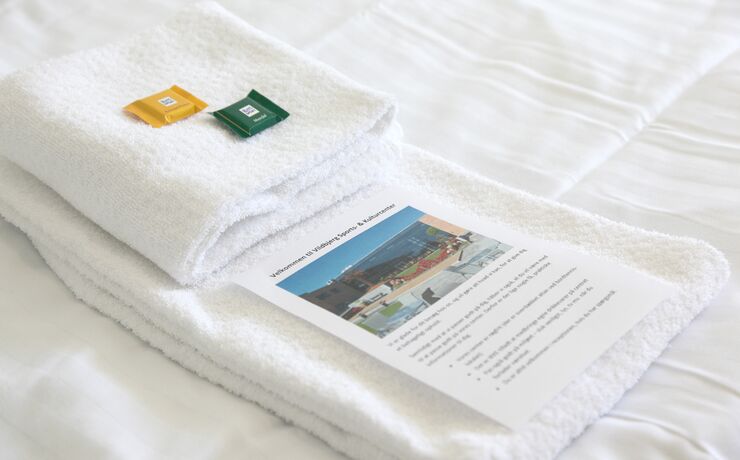 foldede håndklæder på seng med brochure på