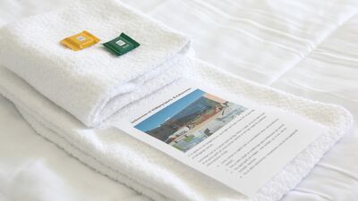 foldede håndklæder på seng med brochure på